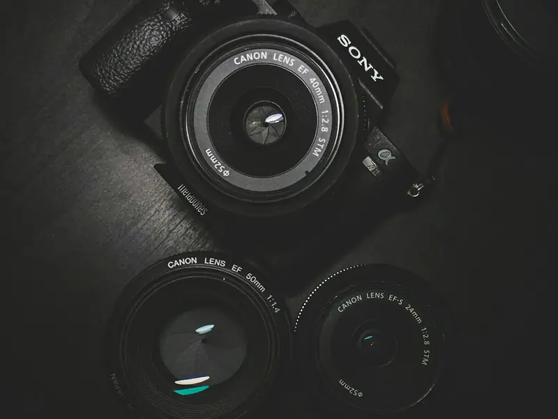 A camera body and two lenses on a dark surface